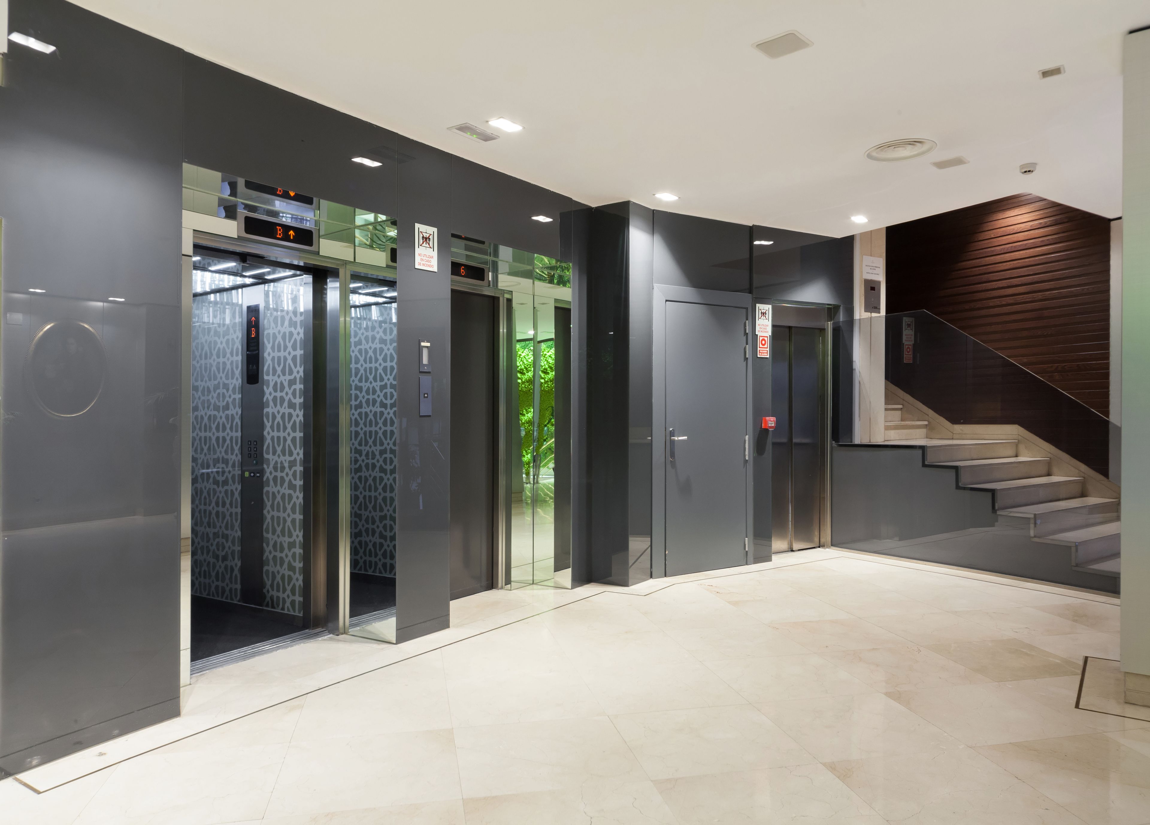 A modern elevator area with glass doors and a staircase.