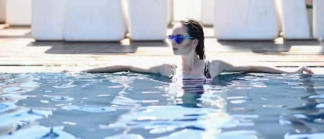 A person in a swimming pool with clear water and a tiled floor.