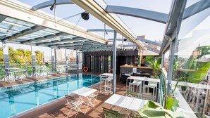 A rooftop pool area with a glass enclosure, seating, and a bar. - Inhala Hotel Garden (Madrid)