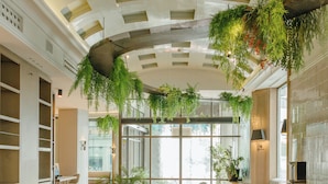 A modern interior with a curved bar, seating, and hanging plants. - Inhala Hotel Garden (Madrid)