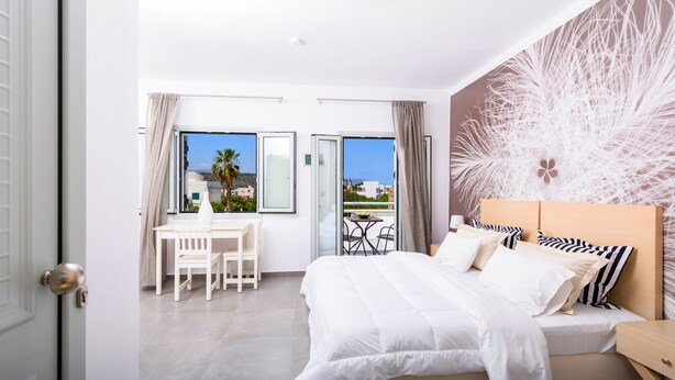 A modern bedroom with a large bed, a desk, and a balcony with a view. - Angela Studios & Apartments (Agios Nikolaos)
