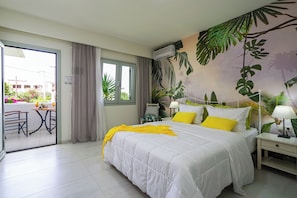 Une chambre d’hôtel avec un lit, une table de chevet, une lampe, une fenêtre et une vue sur le balcon extérieur.