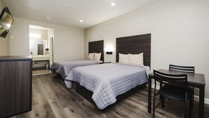 Habitación de hotel con dos camas, un escritorio y una silla.