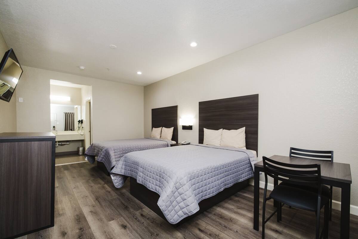 A hotel room with two beds, a desk, and a chair.