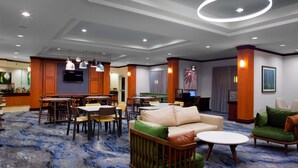 A hotel lobby with a bar area, seating arrangements, and a large screen. - Fairfield Inn & Suites by Marriott Montgomery EastChase Pkwy (Montgomery)