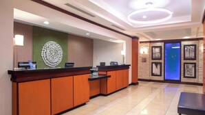 A hotel reception area with a modern design, featuring a reception desk, a large decorative wall, and a blue-lit door. - Fairfield Inn & Suites by Marriott Montgomery EastChase Pkwy (Montgomery)
