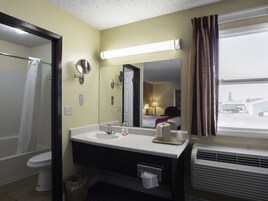 Un baño de hotel con lavamanos, espejo y retrete.