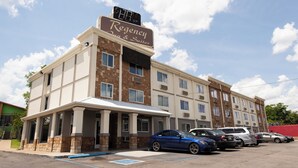A Regency Inn & Suites with a brick facade, multiple windows, and a parking lot with several cars. - Regency Inn And Suites Nashville (Nashville)
