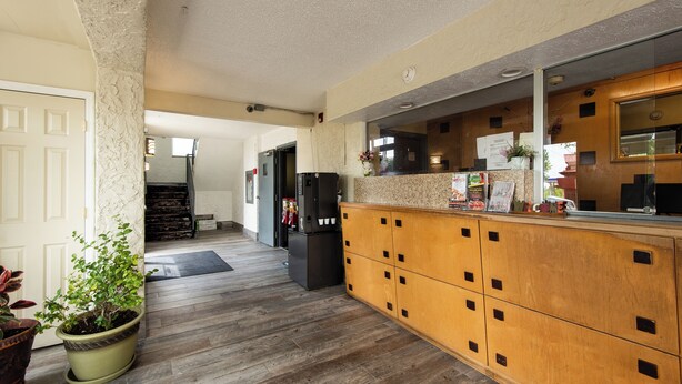 A hotel lobby with a wooden reception desk, a potted plant, and a refrigerator. - Regency Inn And Suites Nashville (Nashville)