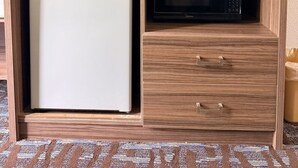 A compact kitchenette with a refrigerator, microwave, and a television on a wooden cabinet. - Regency Inn And Suites Nashville (Nashville)