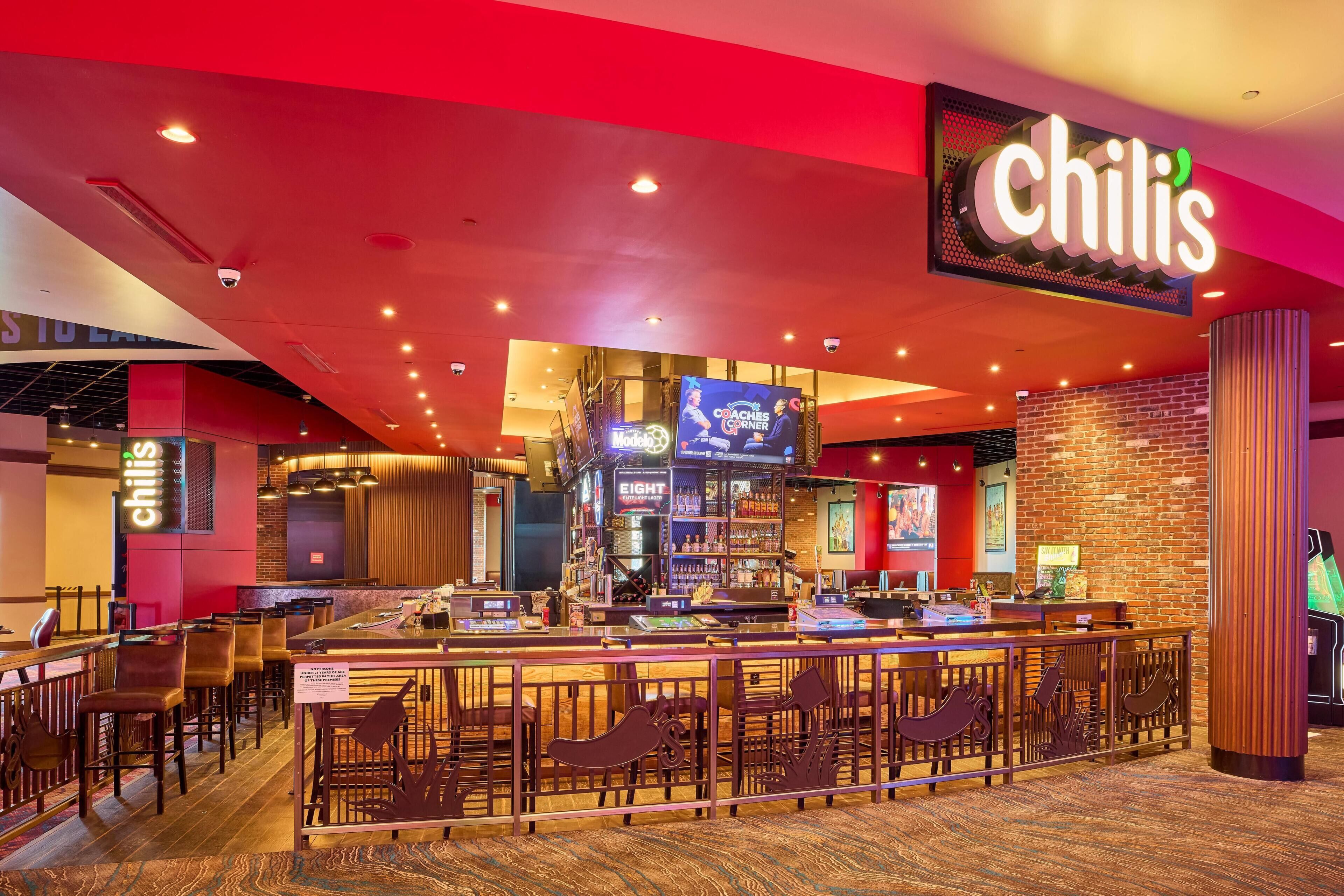 A restaurant with a red and black color scheme, a bar area, and a sign that reads 'chilis.'