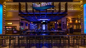 Een bar-restaurant genaamd 'The River' met een modern interieur, meerdere zithoeken en een zichtbare bar.