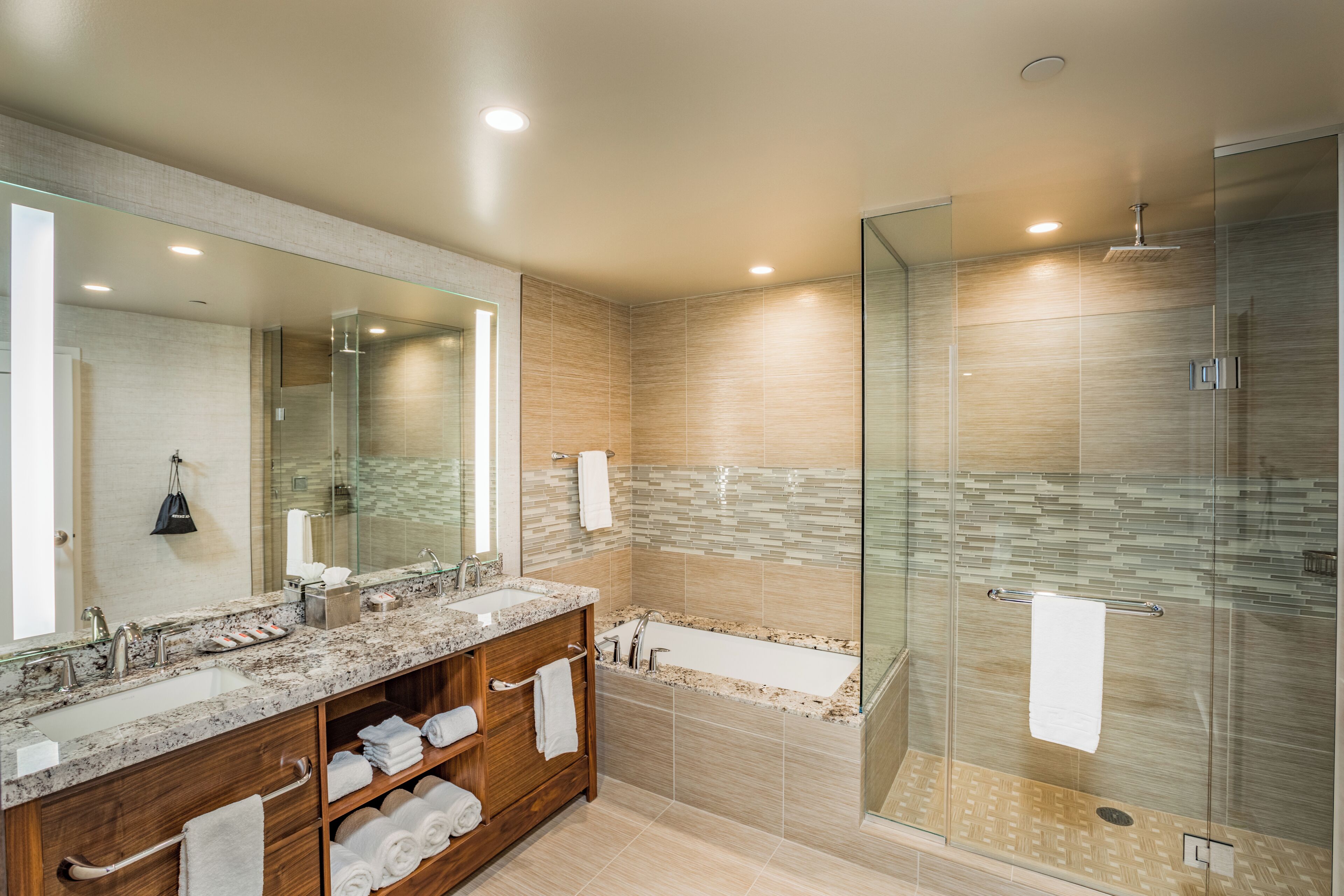 A modern bathroom with a glass-enclosed shower, a large vanity with a sink, and a mirror.