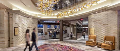 A spacious lobby with a patterned carpet, a cafe named "The Cove Cafe," and a West Tower sign.