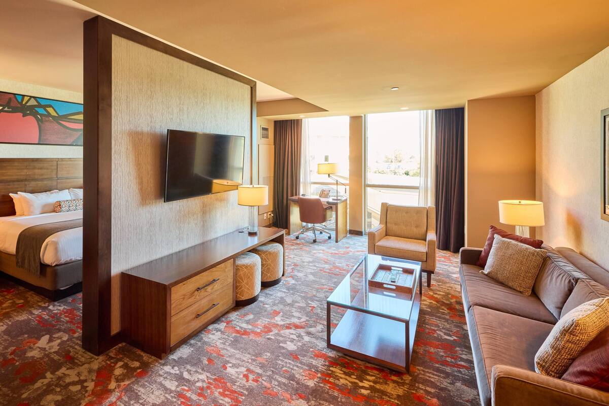 Habitación de hotel con cama, televisor, sofá, mesa de centro y escritorio con silla.