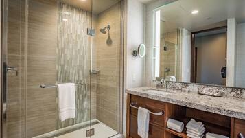 A modern bathroom with a glass-enclosed shower, a vanity with a marble countertop, and a large mirror.