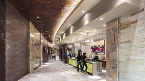 Een moderne hotel lobby met een receptiebalie, een houten plafond en een marmeren vloer.