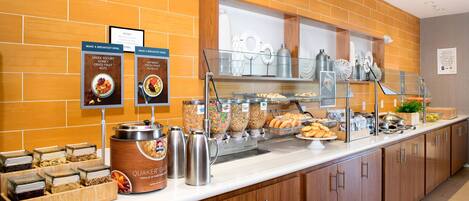 Een ontbijtbuffet met diverse etenswaren, waaronder Griekse yoghurt, granola en vers fruit.