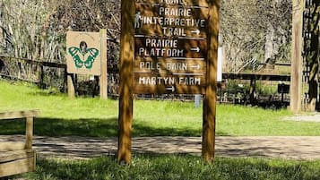 Un cartel de madera con flechas direccionales que señalan a diversos destinos como Discovery Trail, Prairie Interpretive Trail, Prairie Platform, Pole Barn y Martyn Farm.