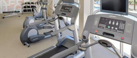 A gym with treadmills, elliptical machines, and a weight bench.