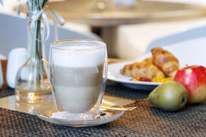 A glass of milk on a saucer, a plate with croissants and fruit, and a vase with dried flowers on a table. - Hestia Hotel Radi un Draugi (Riga)