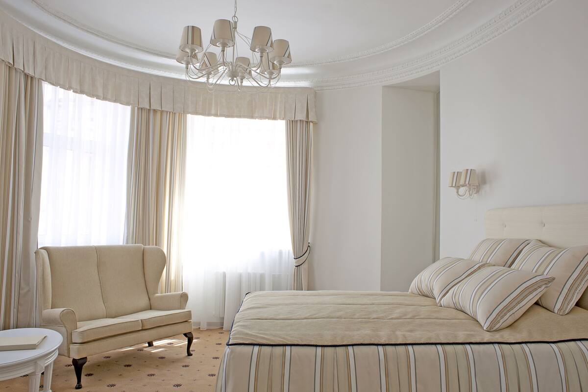 A hotel room with a large bed, a sofa, and a chandelier.