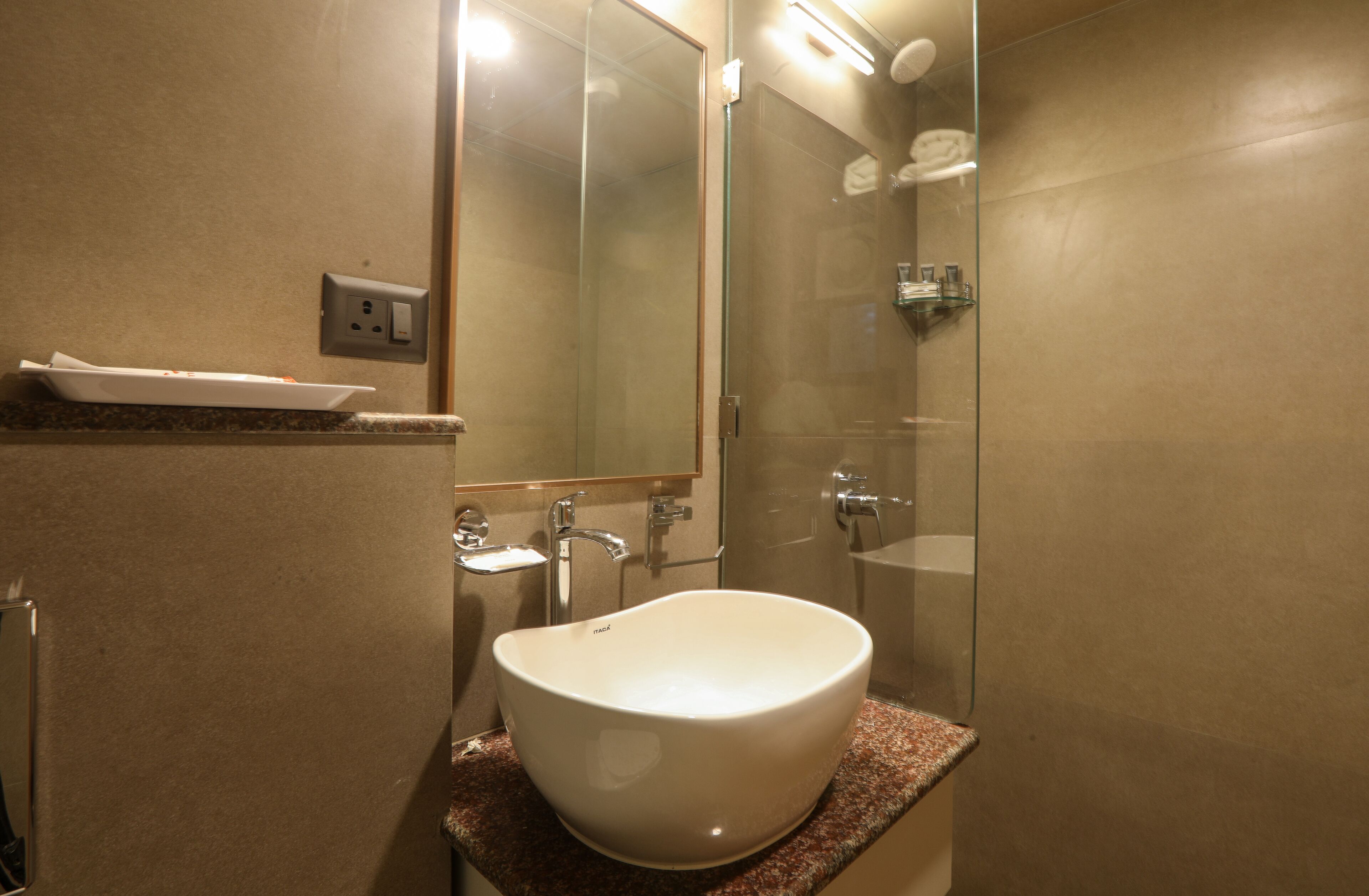 Une salle de bain moderne avec un grand lavabo blanc, une douche en verre et un comptoir en marbre.