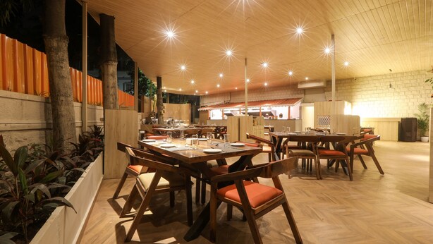 Un restaurante con mesas y sillas de madera, un muro de ladrillo y un techo con luces en forma de estrella.