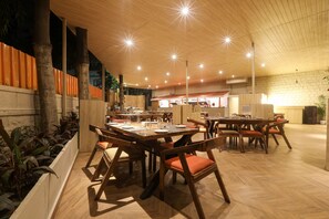 Un restaurante con mesas y sillas de madera, un muro de ladrillo y un techo con luces en forma de estrella.