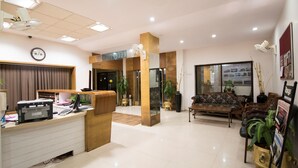 Zona de recepción de hotel con mostrador, un sofá y una mesita de centro.
