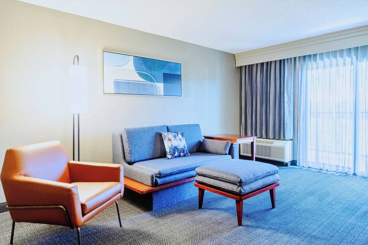 A modern hotel room with a sofa, armchair, and a small table.