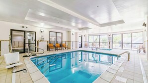 A large indoor swimming pool with clear water, surrounded by lounge chairs and a sunlit room with a large window. - Courtyard by Marriott Biloxi North/D'Iberville (D'Iberville)