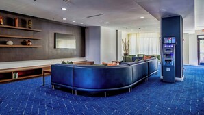 A modern lobby with a curved seating area, a flat-screen TV, and an ATM. - Courtyard by Marriott Biloxi North/D'Iberville (D'Iberville)