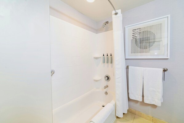 A modern bathroom with a bathtub, a shower, and a framed artwork on the wall.