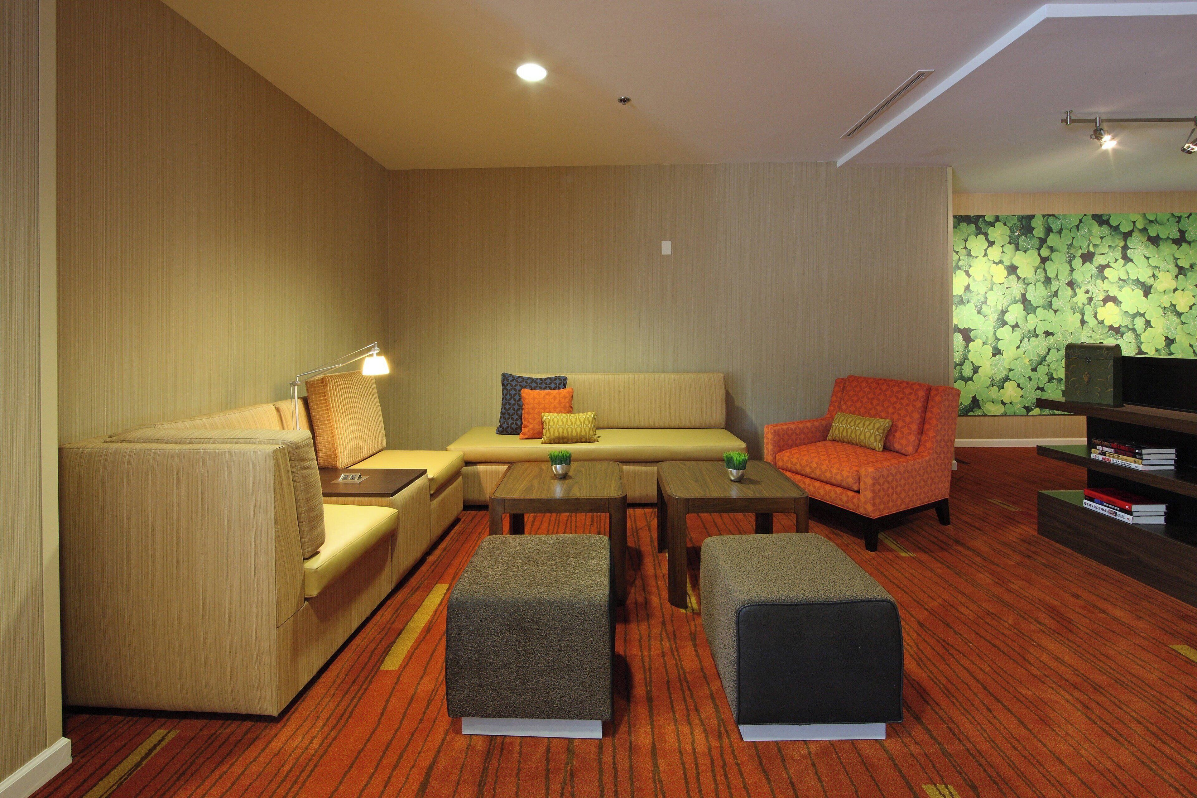 A modern living room with a sofa, armchair, ottomans, and a coffee table.