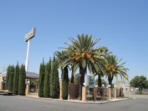 A hotel entrance with palm trees, a gated driveway, and a clear blue sky. - Stage Stop Inn Williams (Williams)