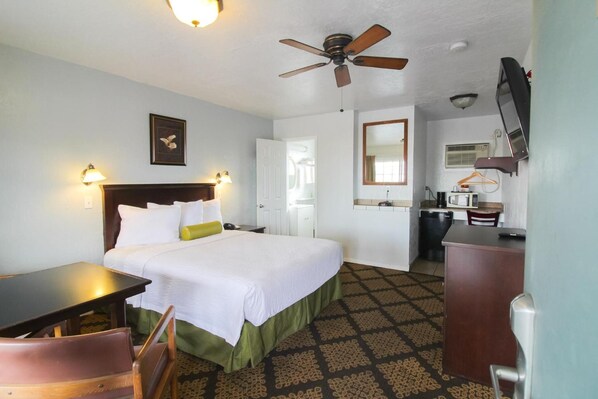 A hotel room with a bed, a desk, a chair, a ceiling fan, a television, and a mirror. - Stage Stop Inn Williams (Williams)