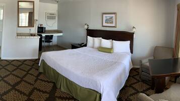A hotel room with a bed, a desk, a chair, a TV, a mirror, and a window.