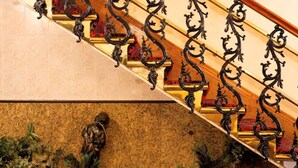 A grand staircase with ornate black metal railings and red cushioned steps. - Aspen Apartments (London)