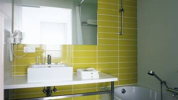 Un baño con paredes de azulejos amarillos, un lavamanos blanco, un espejo y una bañera.