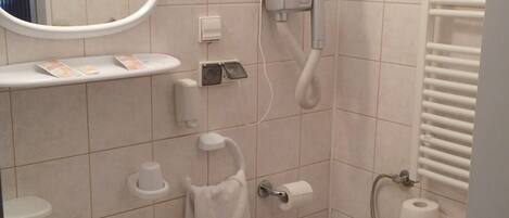 A bathroom with a sink, mirror, towel rack, toilet, and a hairdryer.