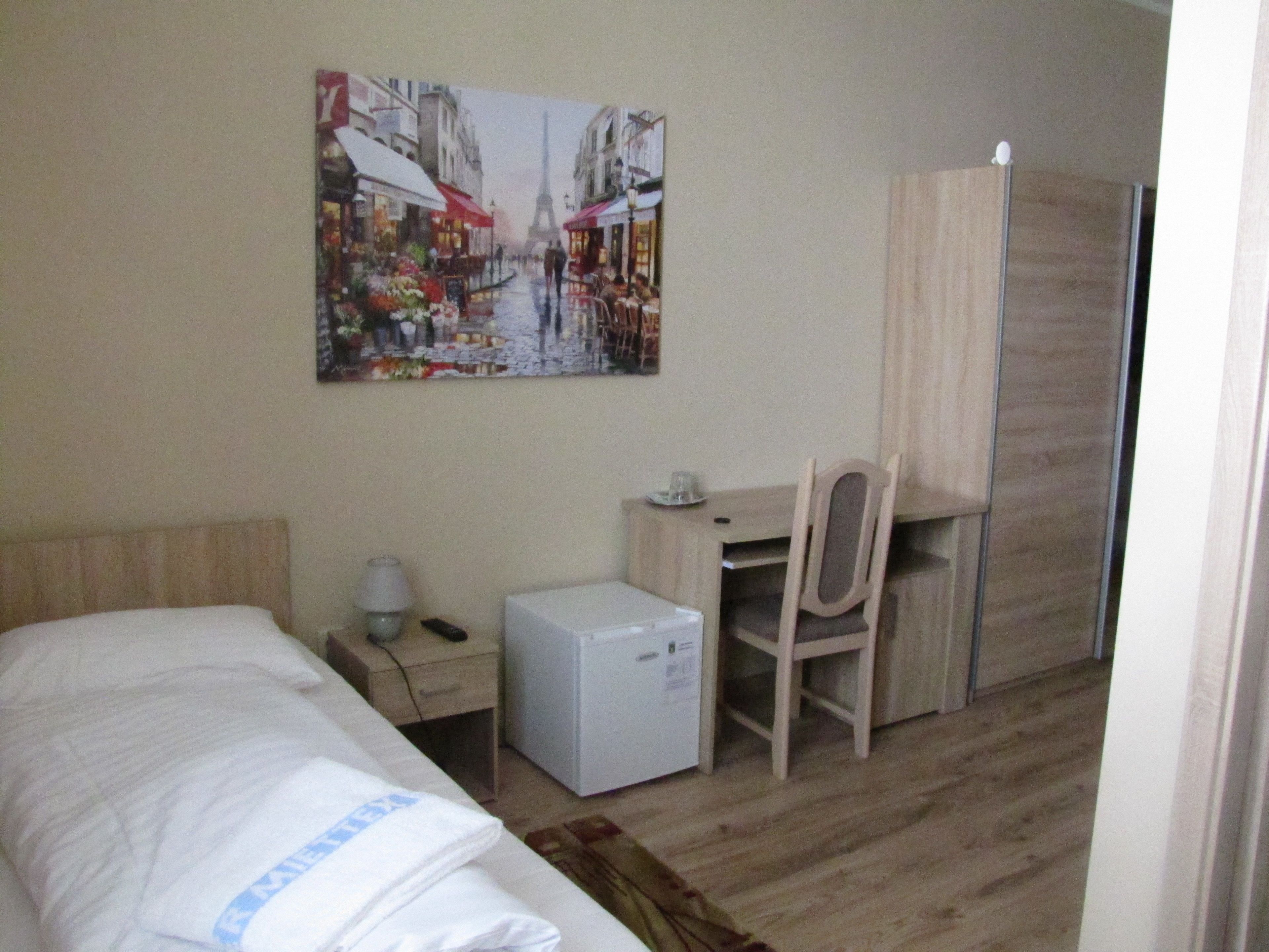 Ein Hotelzimmer mit Bett, Schreibtisch, Stuhl, kleinem Kühlschrank und Kleiderschrank.