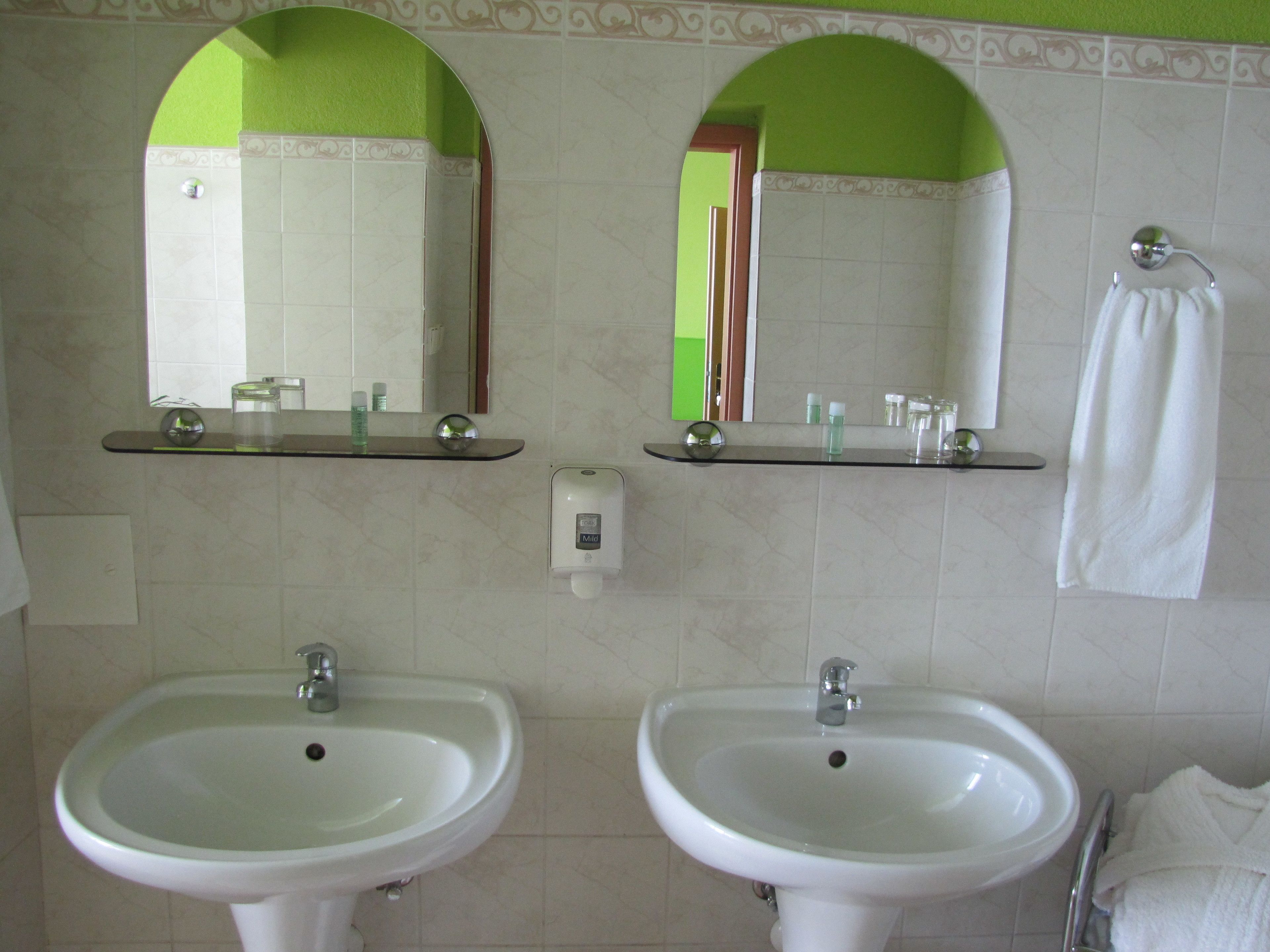Un baño con dos lavamanos, un espejo y un perchero para toallas.
