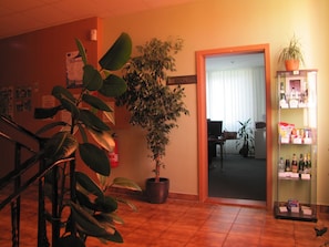 Un hall d’entrée avec un escalier, une grande plante en pot, un comptoir de réception et un distributeur automatique.