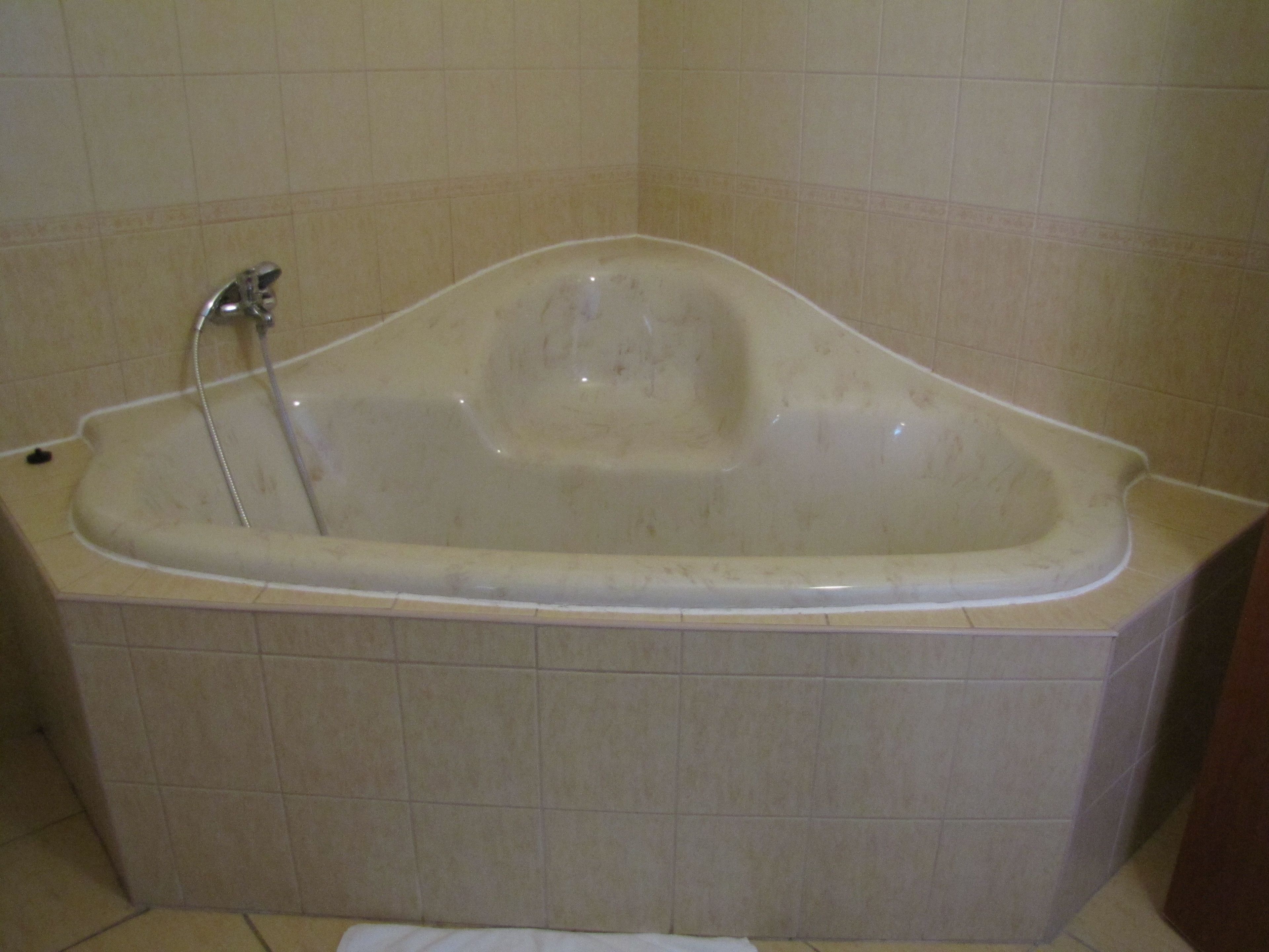 Een standaardbad in een badkamer met beige tegels.