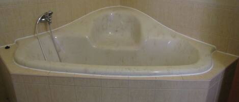 A standard bathtub in a bathroom with beige tiles.