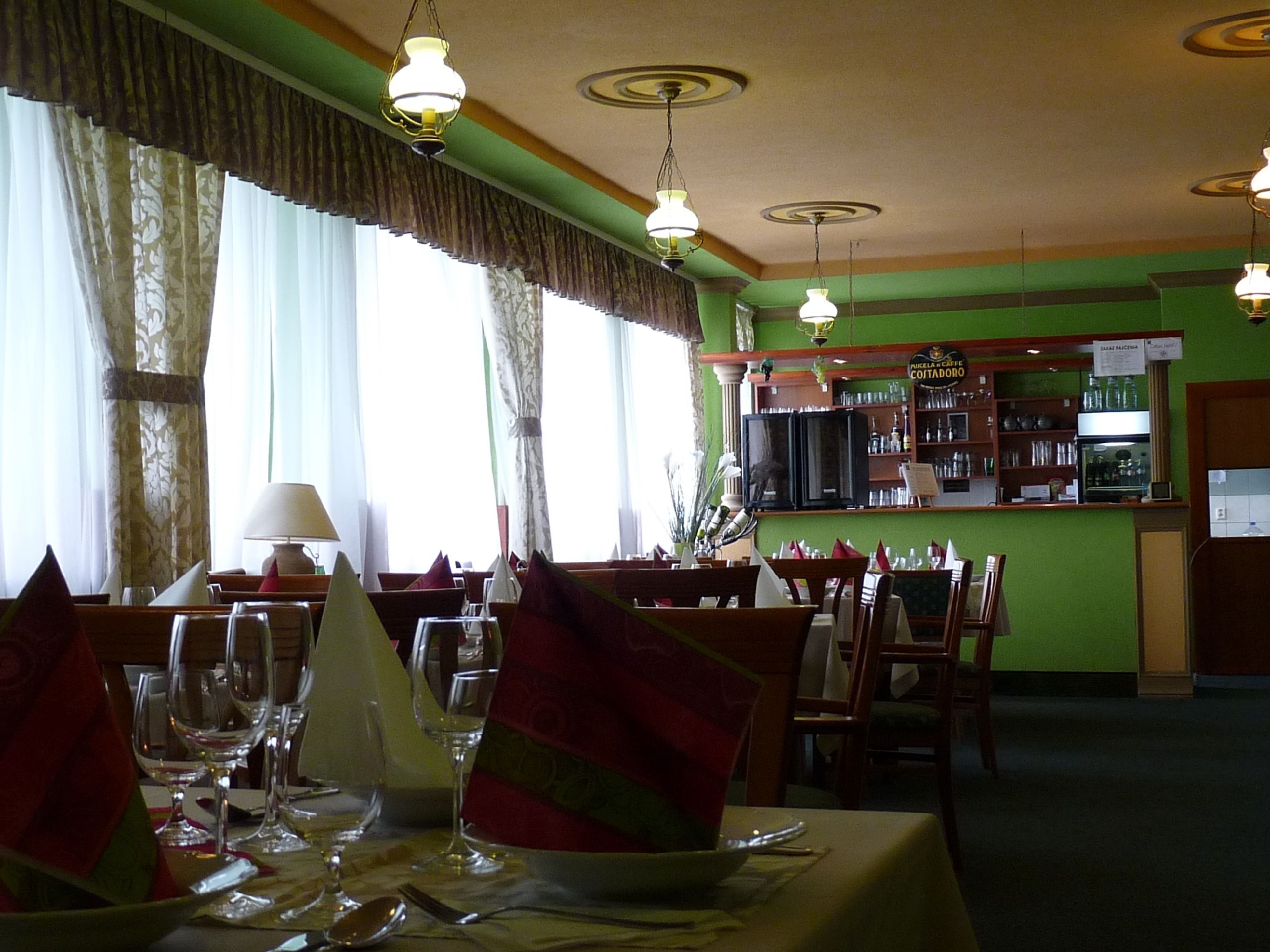 A restaurant with tables set for dining, a bar area, and a view of the street outside.
