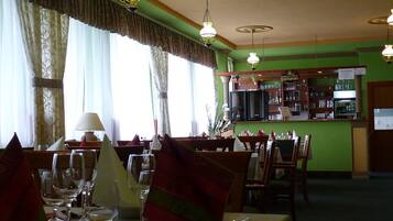 A restaurant with tables set for dining, a bar area, and a view of the street outside.