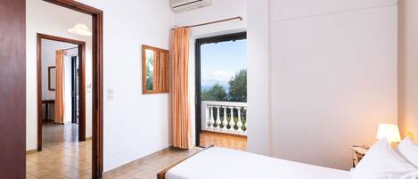 A hotel room with two beds, a balcony with a railing, and a view of the outdoors.