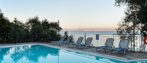 Piscina a l'aire lliure de temporada, para-sols i gandules